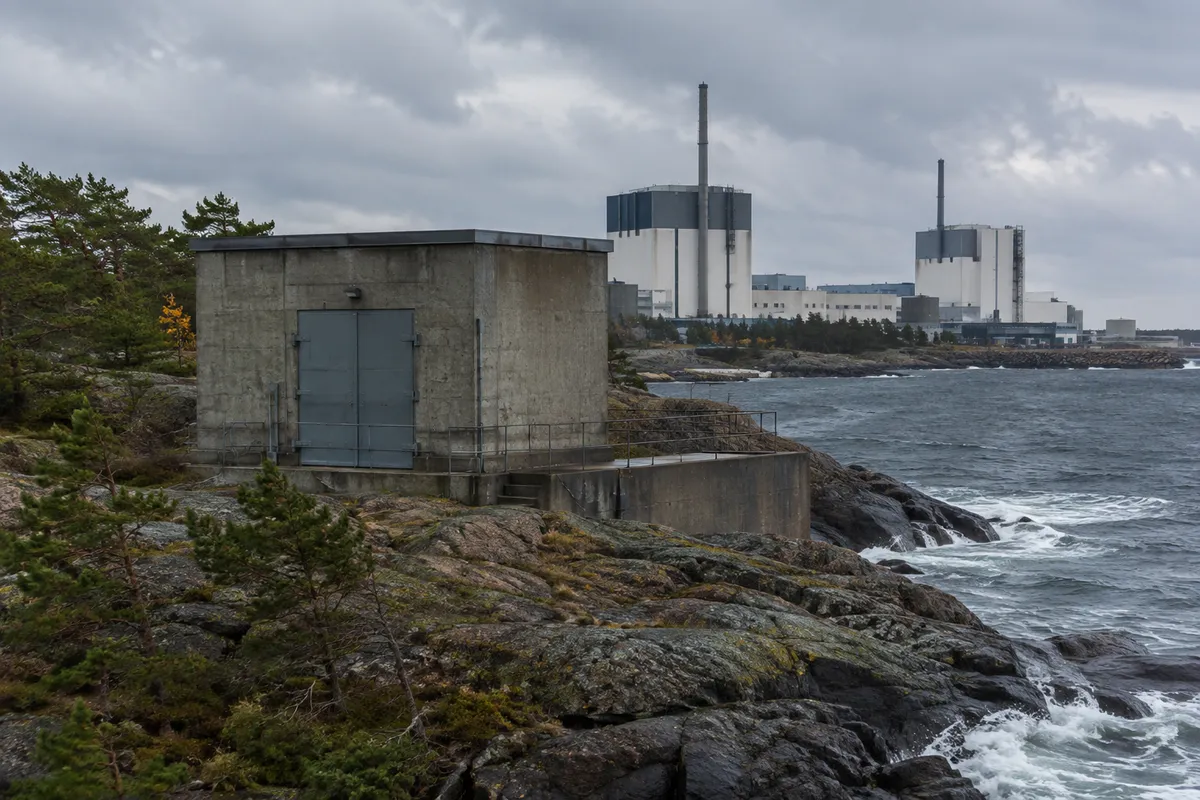 Fristående betongbyggnad vid ett svenskt kärnkraftverk på en klippig kust en blåsig dag