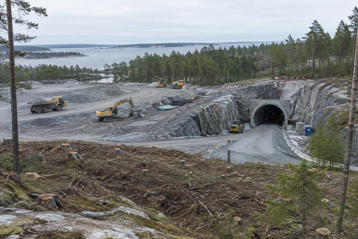 Byggarbetsplats i en tallskog där en ramp leder ner i berget