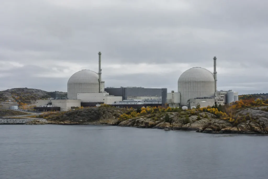 Kärnkraftverk med två kupolformade reaktorbyggnader vid en klippig kust en mulen höstdag