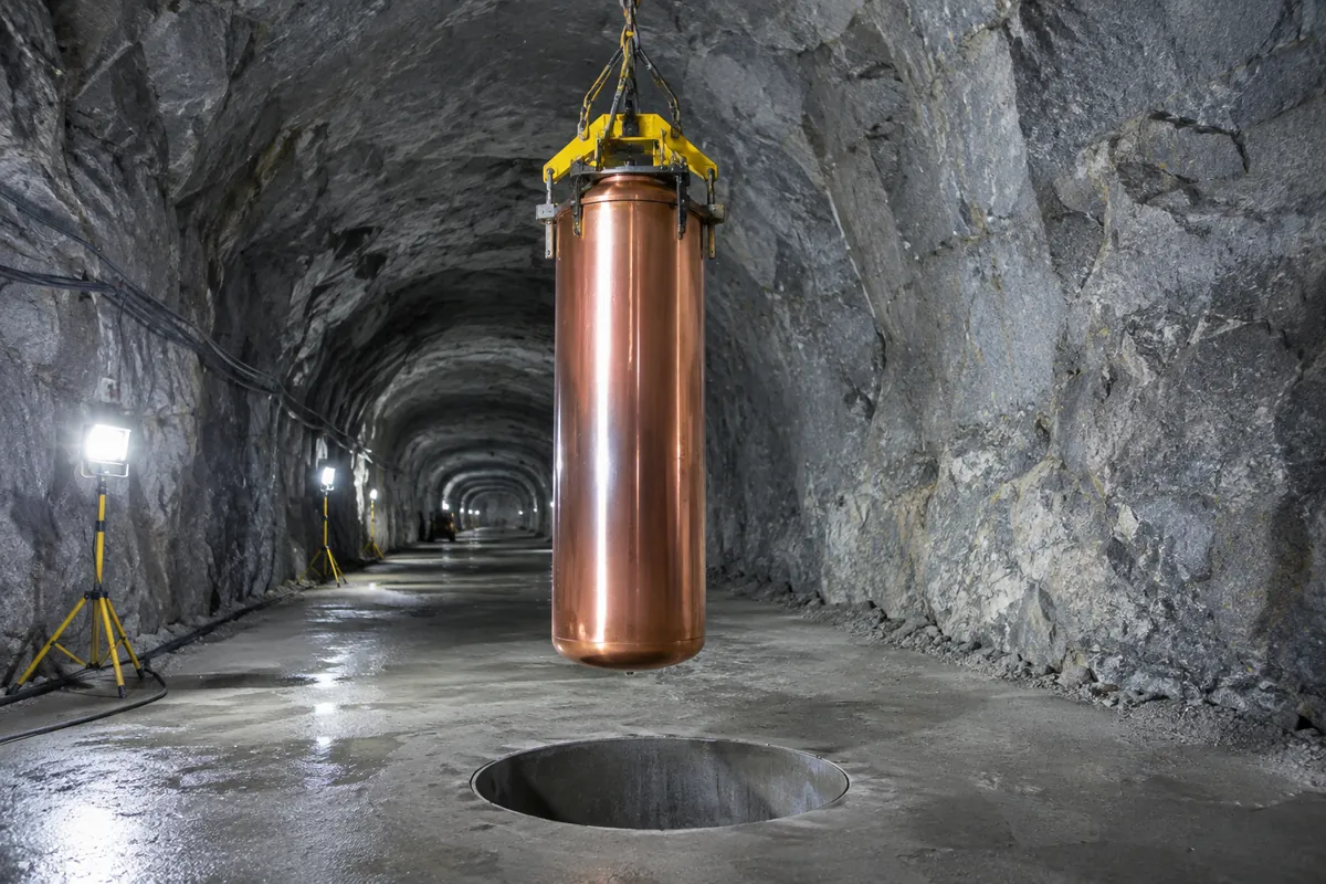 Kopparkapsel som sänks ner i ett borrat hål i golvet i en bergtunnel