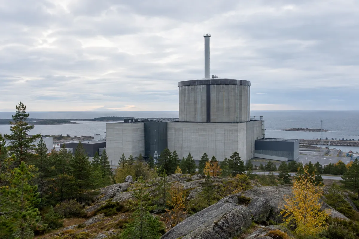 Reaktorbyggnad vid ett svenskt kärnkraftverk vid kusten med betongfasad och tallar i förgrunden