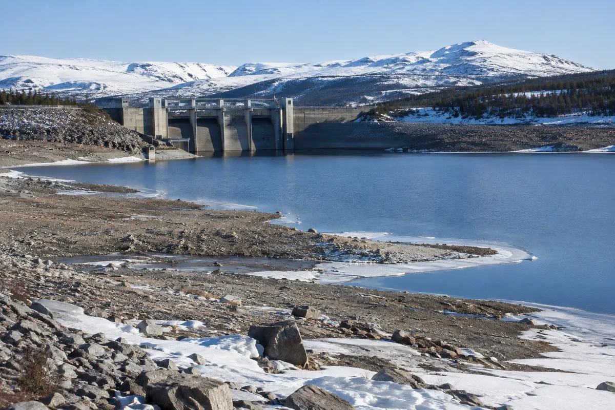 Regleringsdamm vid ett vattenkraftsmagasin i Lappland med låg vattennivå på senvintern