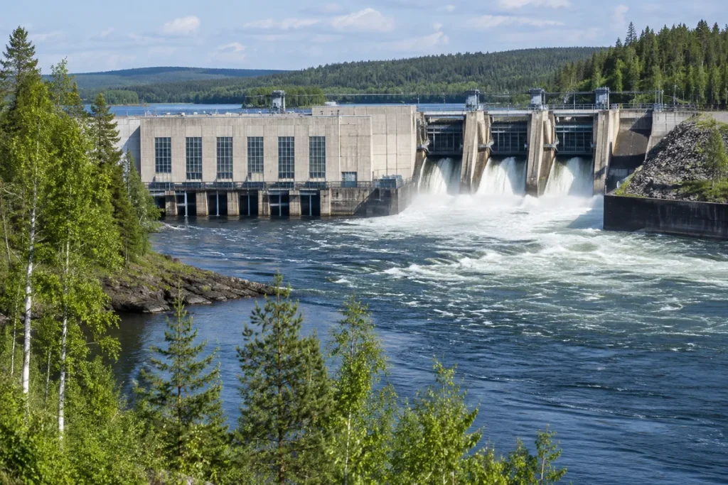 Vattenkraftverk vid en bred älv i Norrland med vatten som forsar genom utskovet
